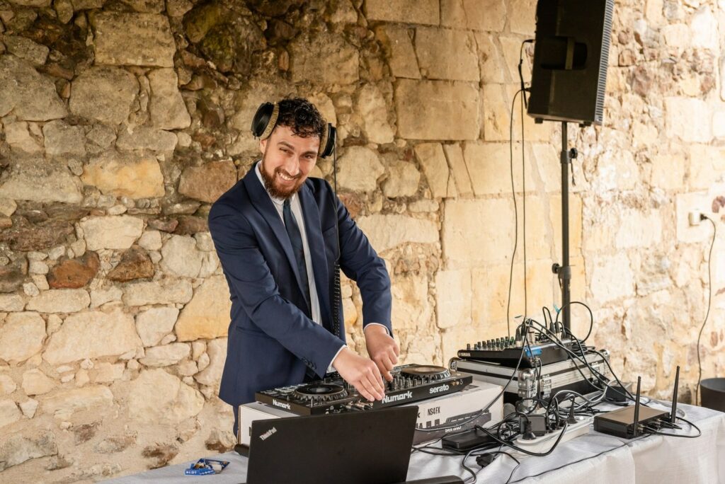 Maxime Perez, DJ Perez, en train de mixer devant un mur en pierre
